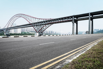 Fototapeta na wymiar empty asphalt road with steel bridge of modern city