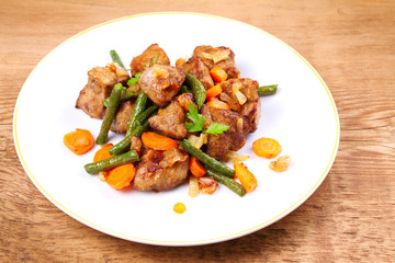 Beef liver with vegetables: carrot, onion and green beans on white plate, horizontal