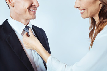Cheerful lady adjusting necktie of man