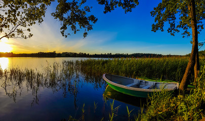 Boat by the lake at sunset - obrazy, fototapety, plakaty