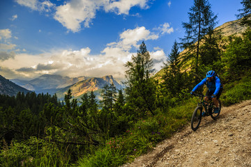 Fototapeta premium Tourist cycling in Cortina d'Ampezzo, stunning rocky mountains on the background. Man riding MTB enduro flow trail. South Tyrol province of Italy, Dolomites.
