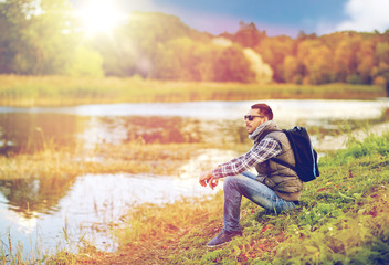 Naklejka na ściany i meble man with backpack resting on river bank
