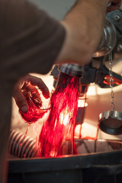 Winemaker holds glass under stream of wine from faucet