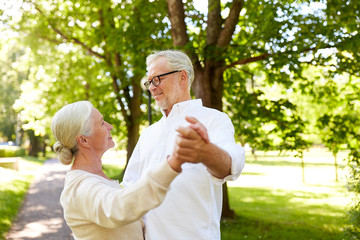 happy senior couple dancing at summer city park