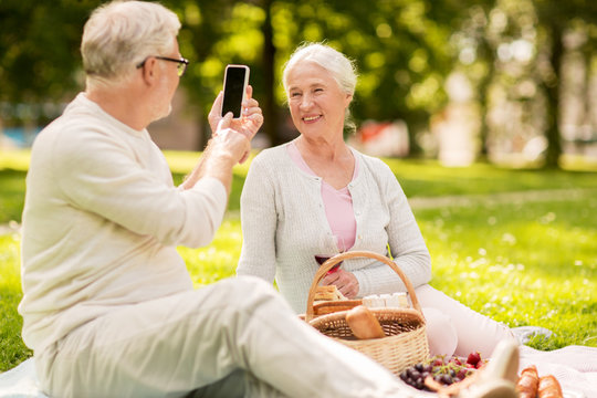 senior couple taking picture by smartphone at park