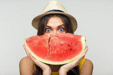 Woman holding red watermelon against face.
