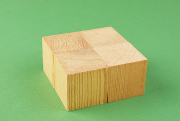 wooden geometric cube on a green background