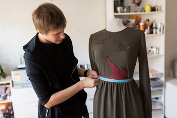 fashion designer with dummy making dress at studio