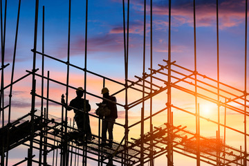 workers and construction site at sunset - obrazy, fototapety, plakaty