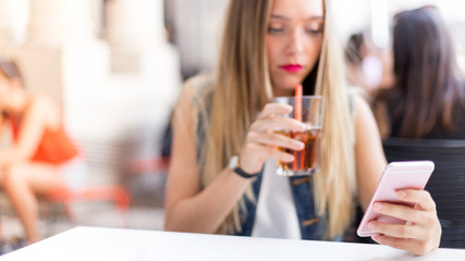 Pensive blonde teenager outdoor with her mobile phone