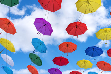 Fototapeta na wymiar Multicolored umbrellas hanging high above the ground