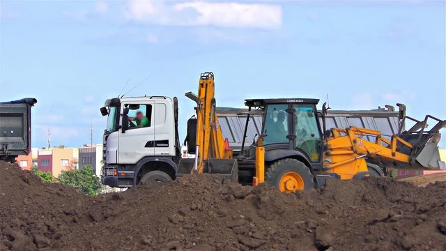 Truck and Excavator with back hoe loading soil, time lapse speed 30x 