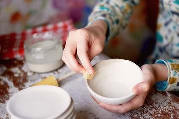 Master ceramist rubs a plate of baked clay. A creative workshop.