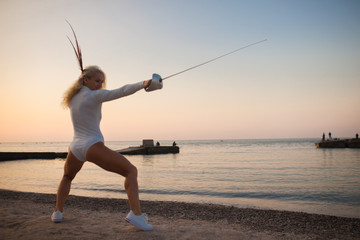 fencer training with a sword by the sea