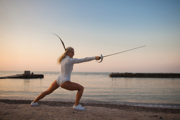fencer training with a sword by the sea