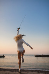 fencer training with a sword by the sea