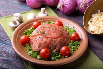 Meat with tomatoes, cheese and mushrooms on a wooden background.