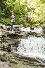 Naklejka premium Girl next to the Waterfall of the bucket in the Selva de Irati in Navarra, Spain.