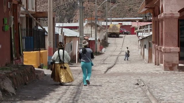 Local women are walking down old pebble street in Putre, Chile