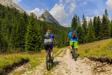 Tourists cycling in Cortina d'Ampezzo, stunning rocky mountains on the background. Man riding MTB enduro flow trail. South Tyrol province of Italy, Dolomites.