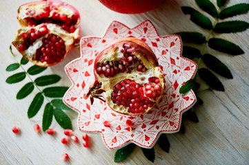 Fresh juicy pomegranate on a light background. On the wooden end of it. Next brush the ash. Healthy...