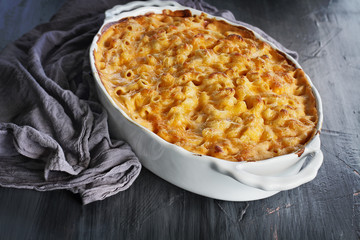 High angel view of a dish of fresh baked macaroni and cheese with table cloth over a rustic dark wood background.