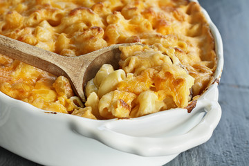 High angel view of a dish of fresh baked macaroni and cheese with a wooden spoon over a rustic dark...