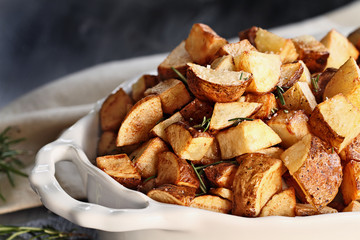 Roasted potatoes quartered and seasoned with rosemary and sea salt. Extreme shallow depth of field with selective focus on foreground.