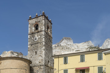 View of the bell tower of the church of San Bartolomeo in the ancient village of Colonnata, Massa Carrara, Tuscany, Italy, against marble quarries in the Apuan Alps