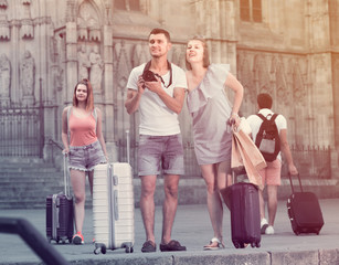 Fototapeta premium Smiling man and woman tourists are holding camera in hands and p