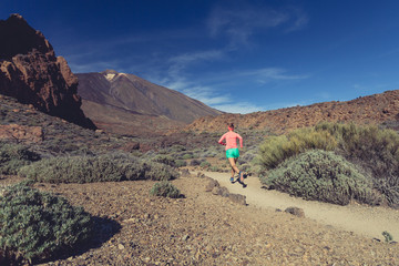 Woman trail running in mountains on sunny day