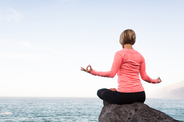 Fototapeta na wymiar Yoga girl meditating and relaxing in yoga pose, ocean view