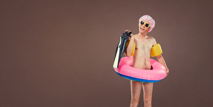 Funny cheerful thin man in a bathing suit with an inflatable cir