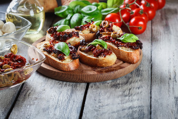 Appetizer bruschetta with sun-dried tomatoes, olives and mozarella.