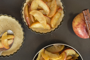 Work with the dough. Form for baking and ingredients for apple pie. The process of preparation of apple tart. View from above. Flat lay.