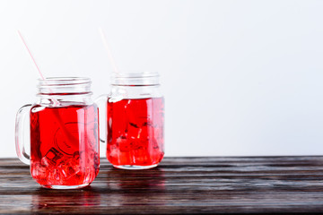 Wooden table top with two mason jars full of lemonade on light background, copyspace for text