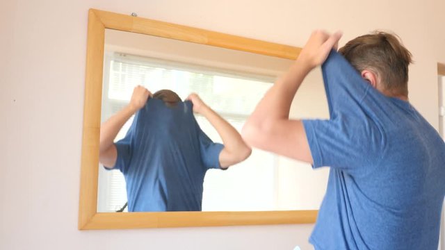 tired unhappy guy undresses in front of a mirror. 4k, slow motion