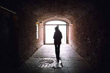 silhouette of young woman in arch of bricks