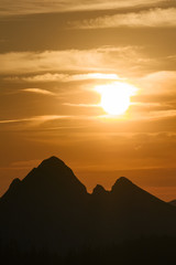 The sun sets over the mountain peaks