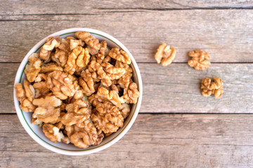 Ceramic bowl full of walnuts on the wooden table