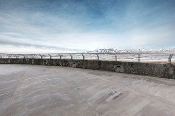 empty concrete floor with white snow mountain in blue sky