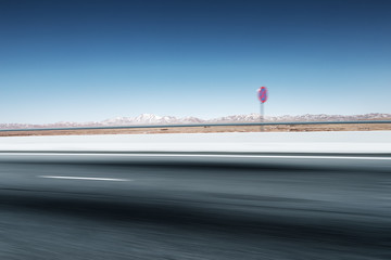 blurred empty asphalt road with snow mountains in blue sky