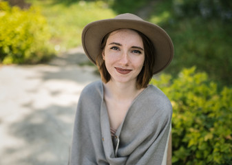 Fashionable young woman wearing in hat and poncho among tropical plants.