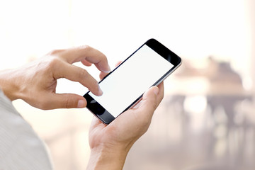Man hands holding blank screen smartphone with blurred background.