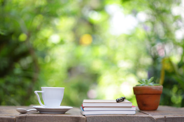 White tea cup with notebooks and plant