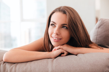 Smiling young woman lying on a pillow on a sofa