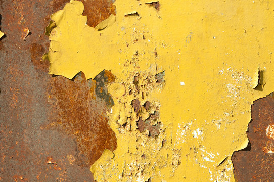 Rusty metal background surface with pealing yellow paint