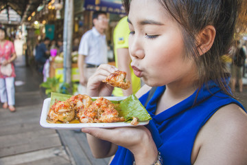 Cute girl of asian blowing for eat Mini Fried Mussels in floating market