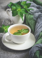 Natural mint tea and fresh mint leaves on a gray background