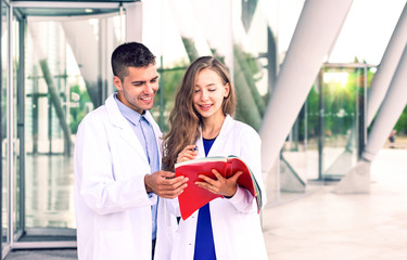 Doctor dentist and assistant nurse looking at papers on modern hospital background                                                                                  